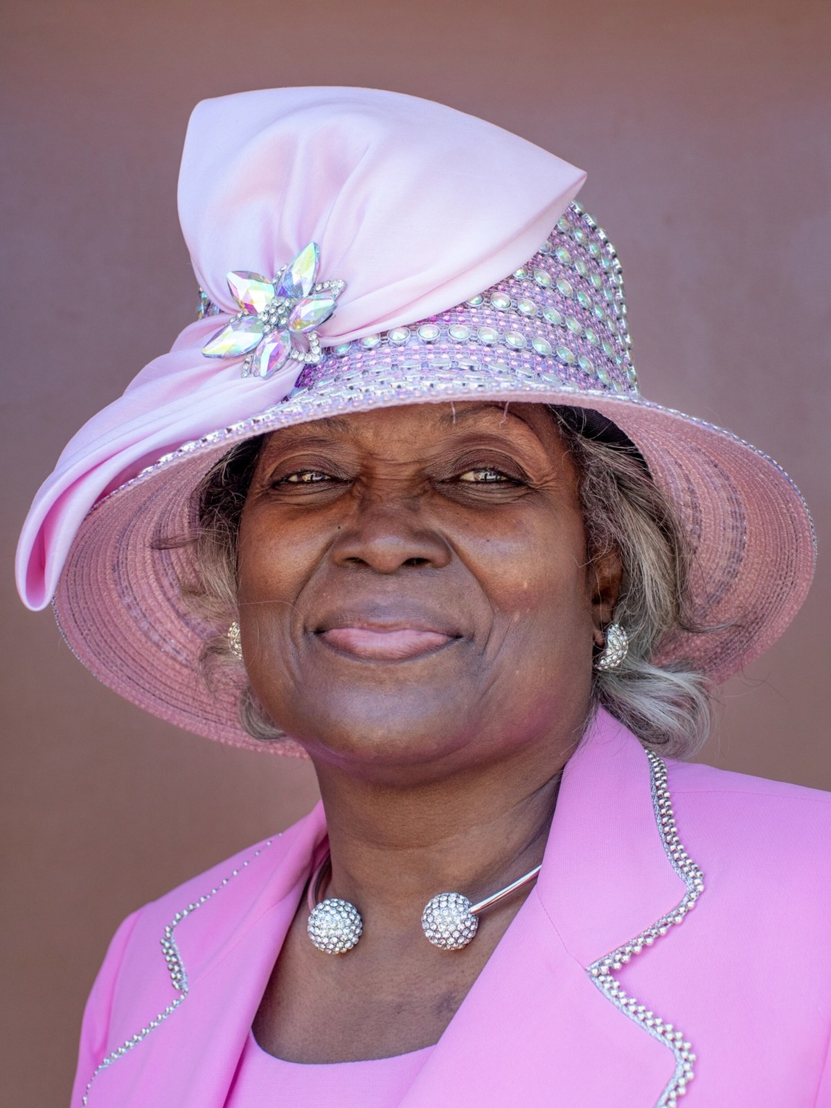 Woman over 70 with pink Hat with Silver Curls Peeking Out — church and Sunday hairstyle for women over 70