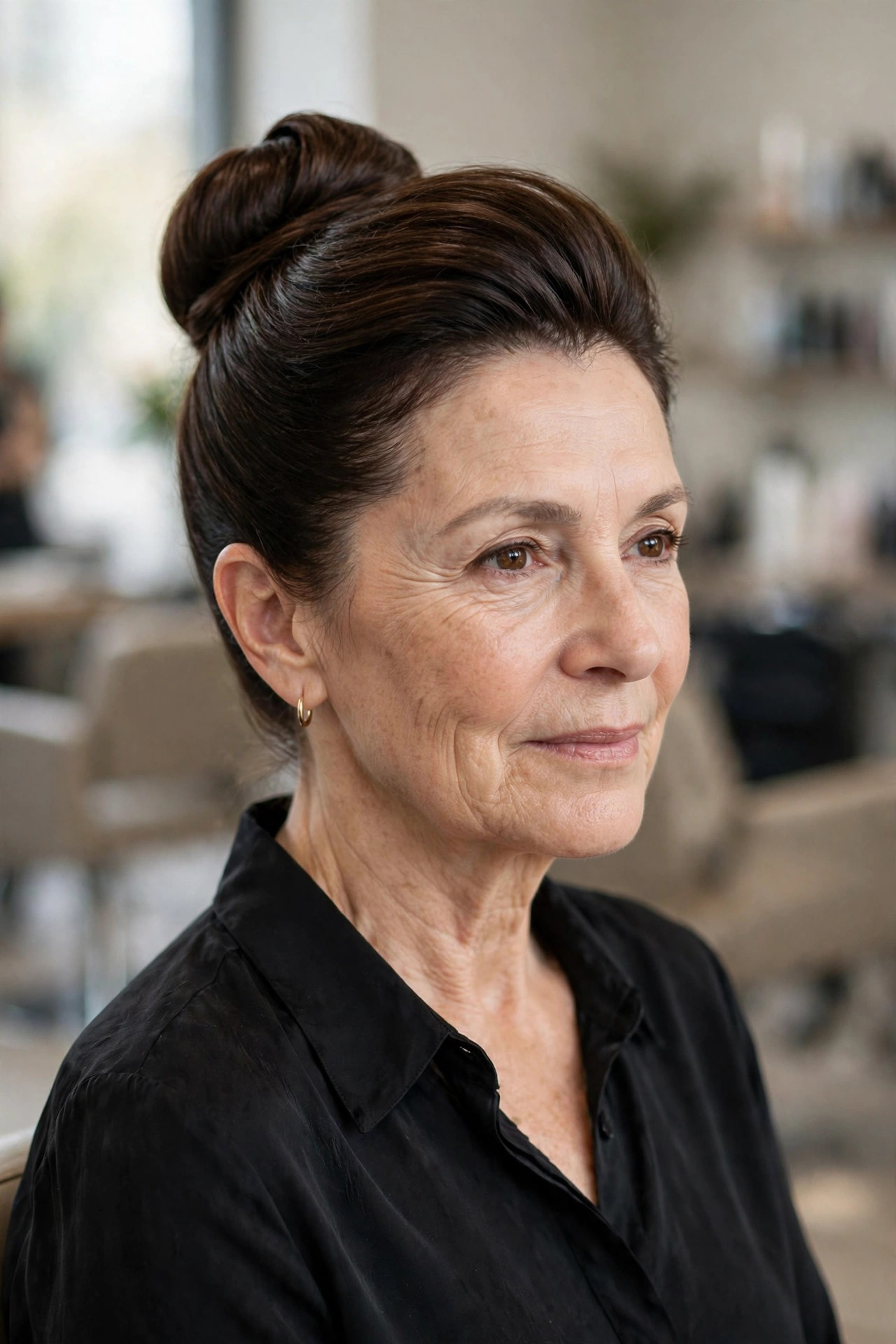 Sleek high bun updo on a woman over 50 with medium dark brown hair