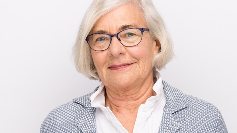 woman over 70 with a feathered white bob wearing blue glasses