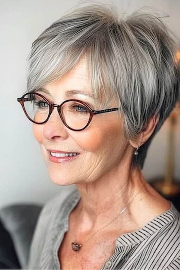 smiling woman over 70 with a gray pixie bob wearing tortoiseshell glasses