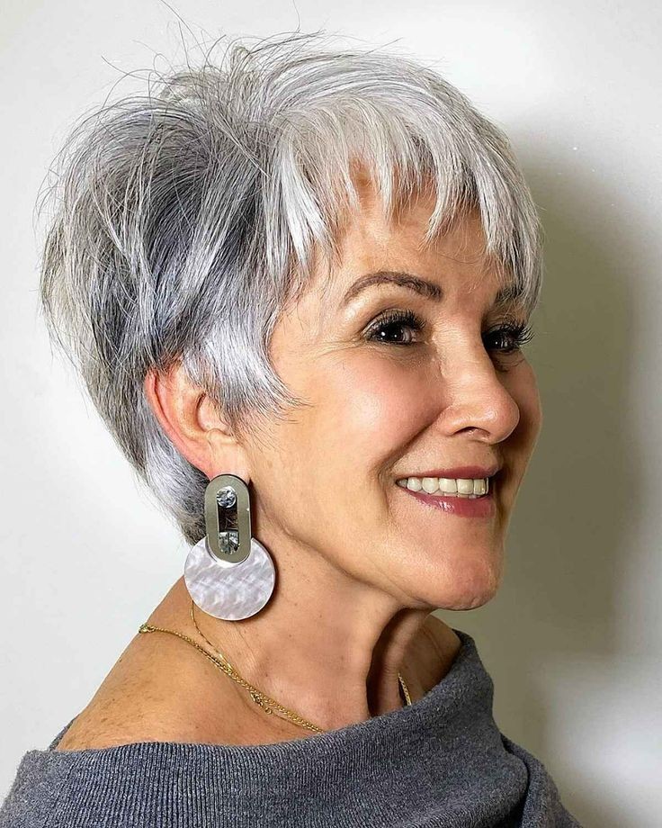 Woman over 70 with a silver pixie with statement earrings — gray pixie hairstyle with soft texture for women over 70