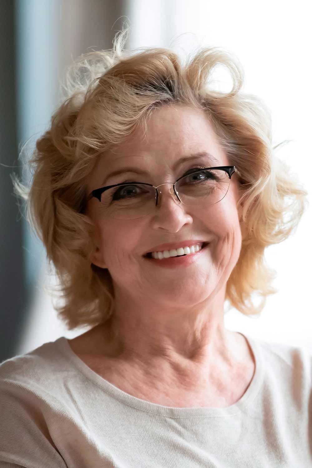 Keeping Colour: Strawberry Blonde Waves With Glasses — woman over 70 comparing going gray versus keeping hair color