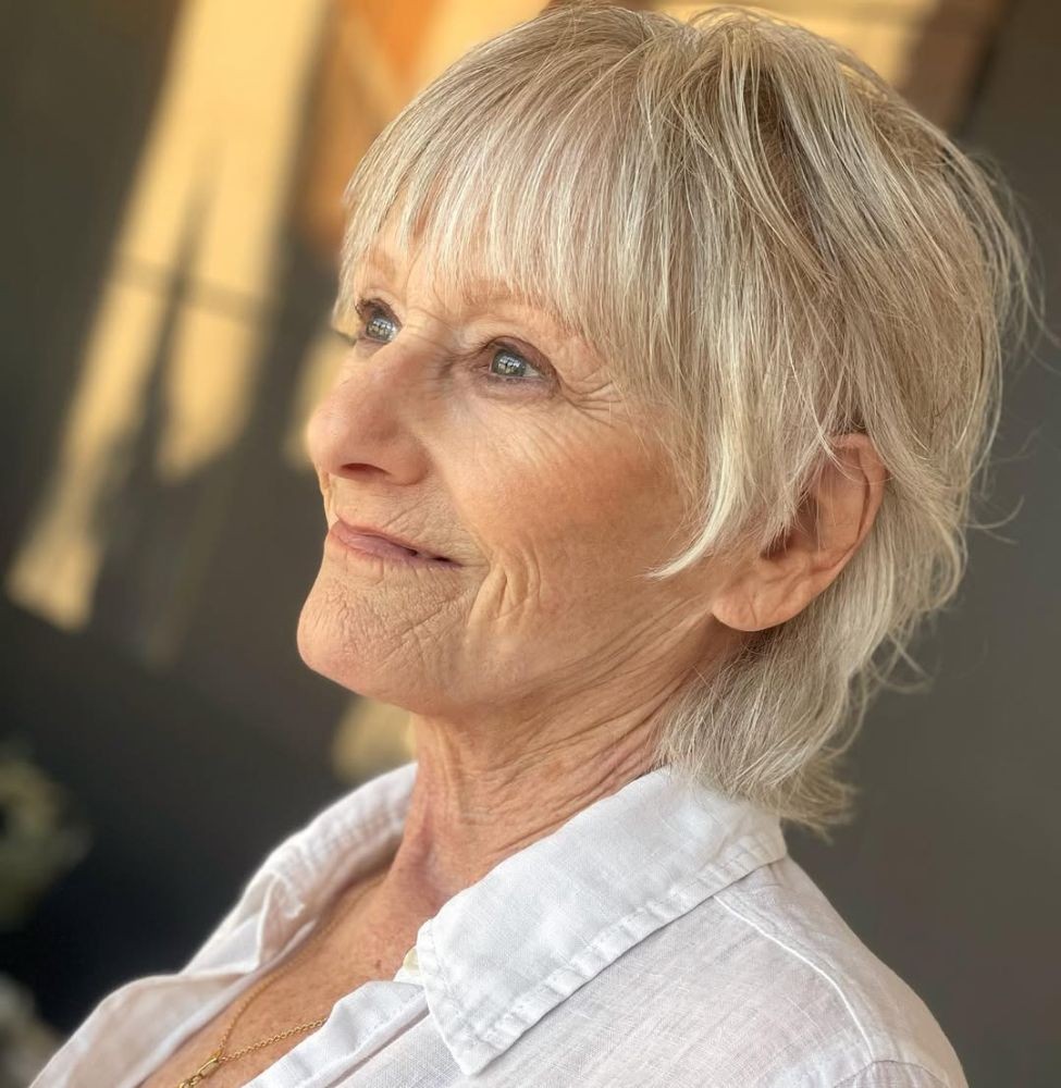 Woman over 70 with golden shaggy layers with soft bangs — flattering bangs hairstyle for women over 70