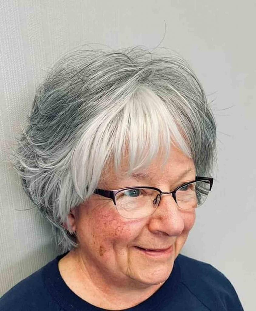 Woman over 70 with natural gray waves with bangs and glasses — flattering bangs hairstyle for women over 70