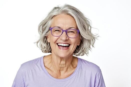 smiling woman over 70 with a silver wavy bob wearing purple glasses