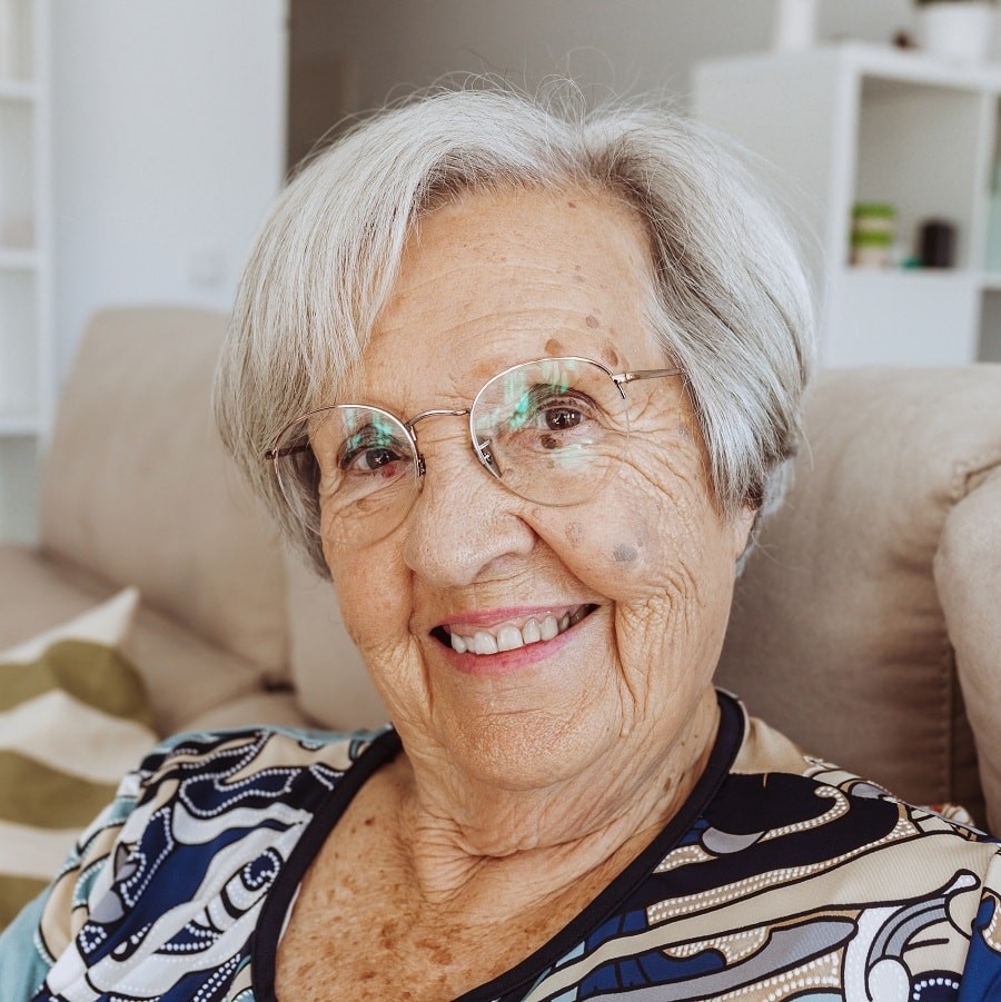 woman over 70 with soft short white layered hair wearing patterned glasses