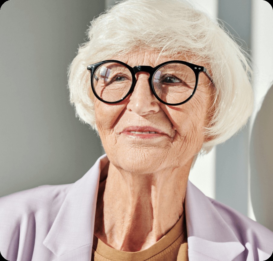 woman over 70 with a fluffy white bob wearing round black glasses