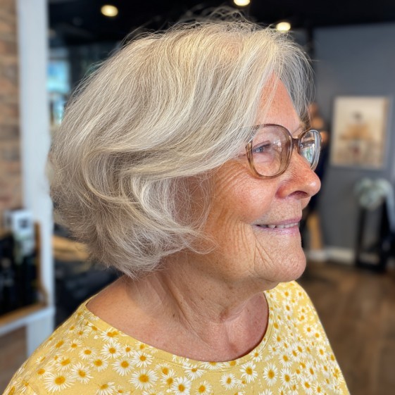 side view of a woman over 70 with a layered blonde bob wearing slim glasses