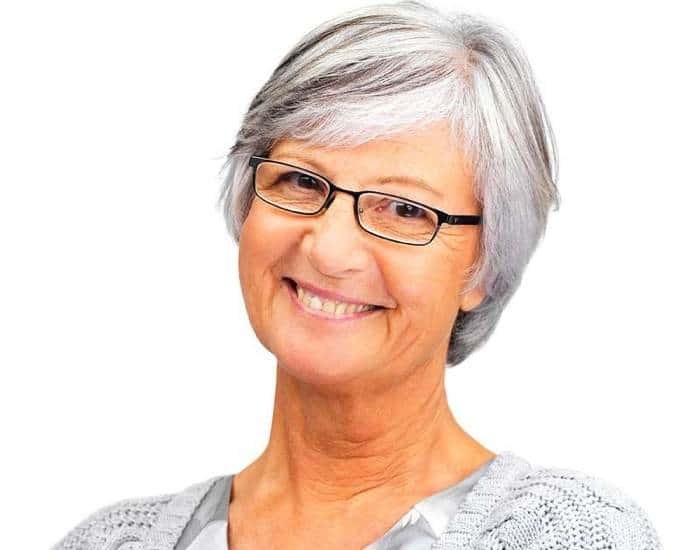 The Layered Gray Bob With Glasses and a Smile — layered haircut that slims a round face on a woman over 70