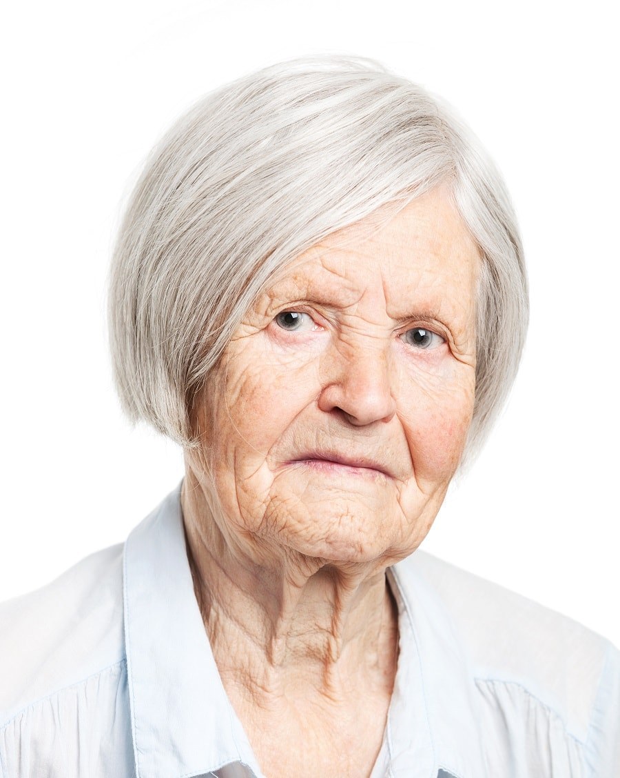 The Straight White Bob With Subtle Layers — layered haircut that slims a round face on a woman over 70