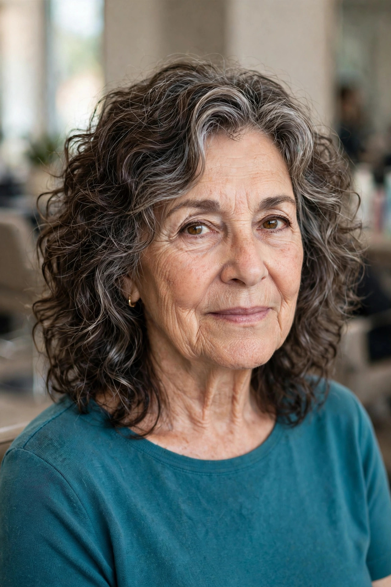 Curly soft medium shag haircut on a woman over 60 with dark hair and silver streaks
