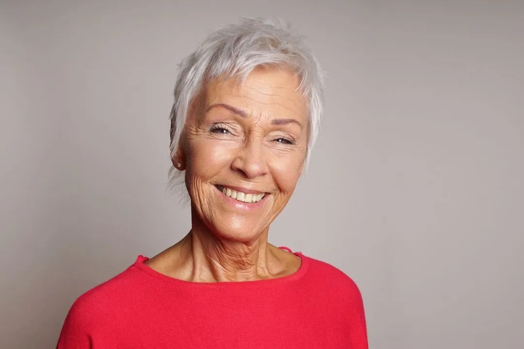 The Short White Crop With a Bright Smile — short haircut on a woman over 70 with a soft jawline