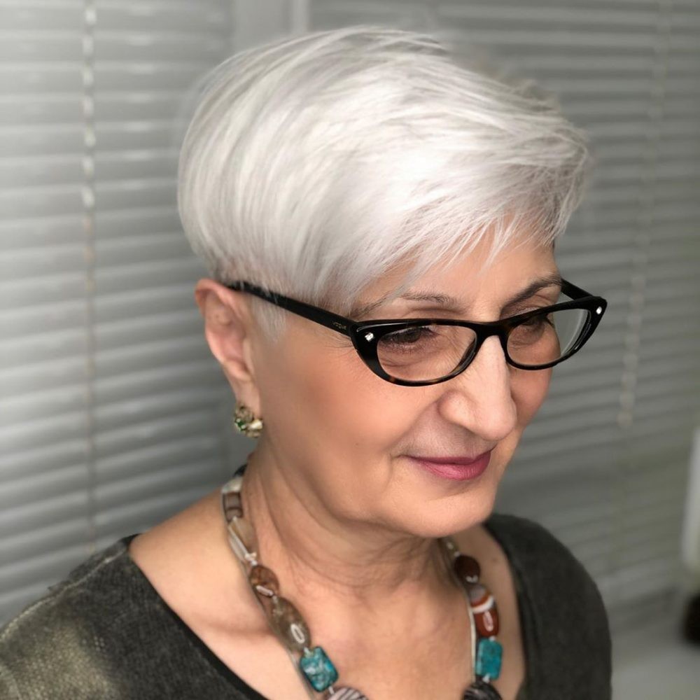 side view of a woman over 70 with a sleek side-parted white pixie wearing black glasses
