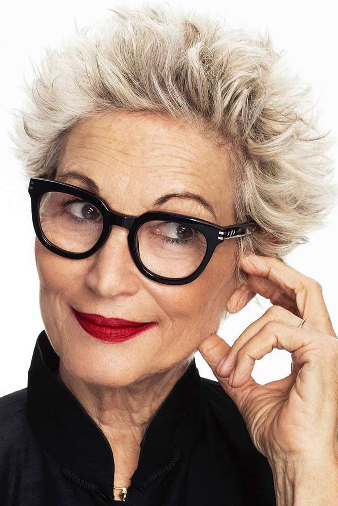 woman over 70 with a blonde spiky pixie cut wearing oversized black glasses