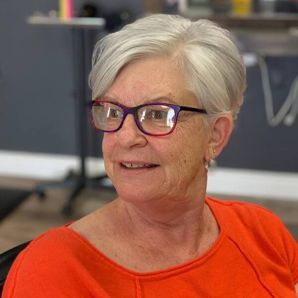woman over 70 with an everyday white pixie cut wearing plum glasses