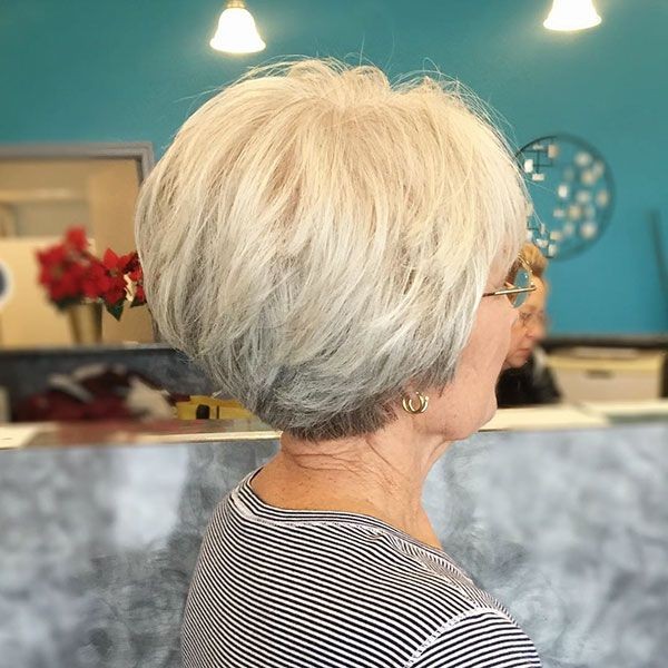 Woman over 70 with a rounded blonde bob in the salon — short layered haircut back view for women over 70