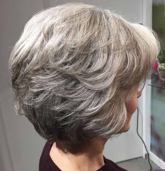 Woman over 70 with a feathered layers with soft waves — short layered haircut back view for women over 70
