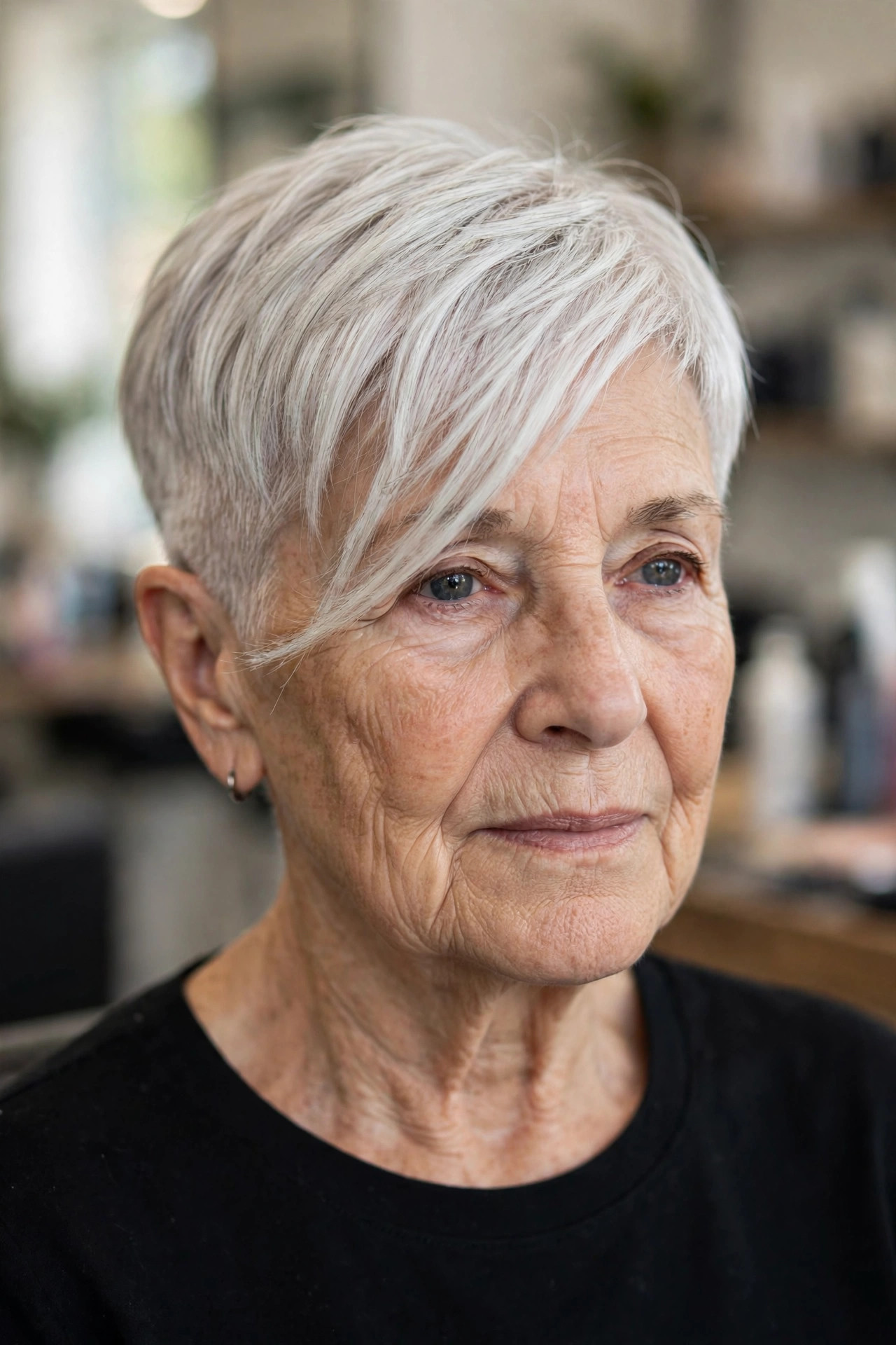 short asymmetric pixie haircut with long sweeping fringe and white silver hair on a woman over 60