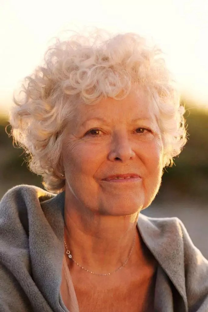 Golden-Hour Blonde Curls — soft perm curls on a woman over 70 with flat hair