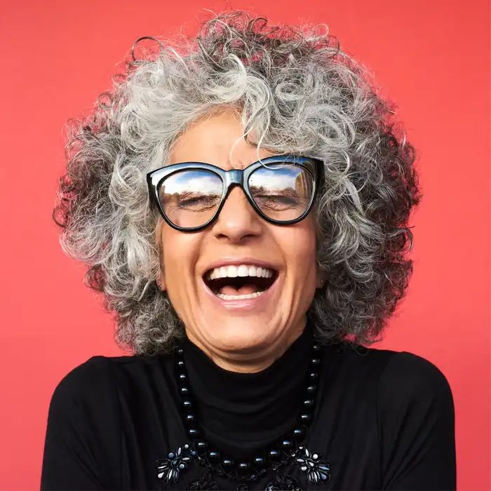 Big Curly Hair With Bold Glasses — stylish haircut on a fashion-loving woman over 70